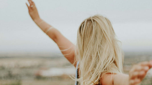 blonde woman standing in a field with arms outstretched