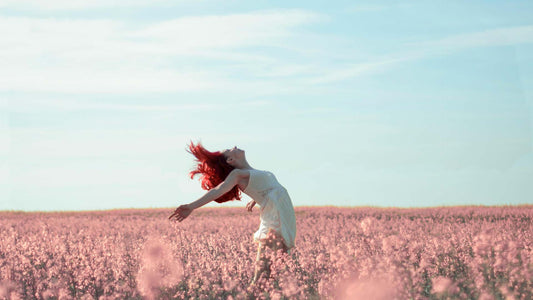 woman in dress with arms out in field of pink flowers