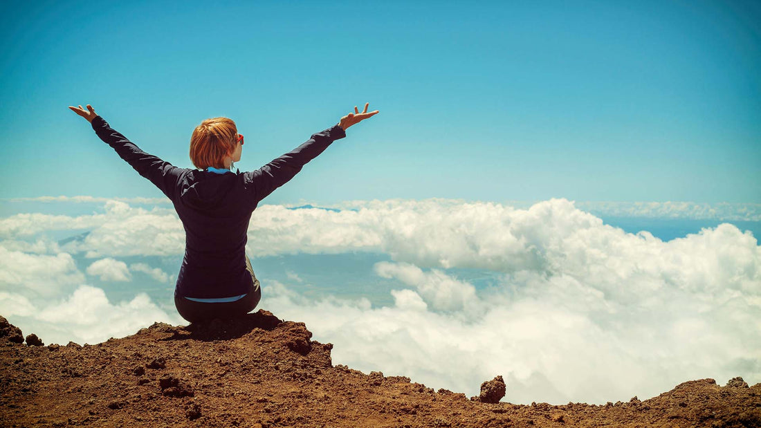 Woman sitting on a cliff with outstretched arms