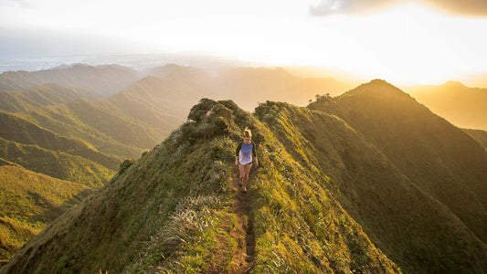 a woman walking on top of a hill at golden hour