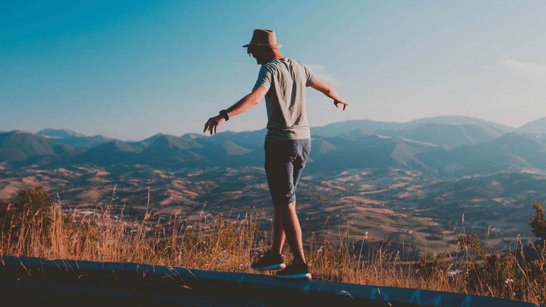 man stands on a hill, arms outstretched