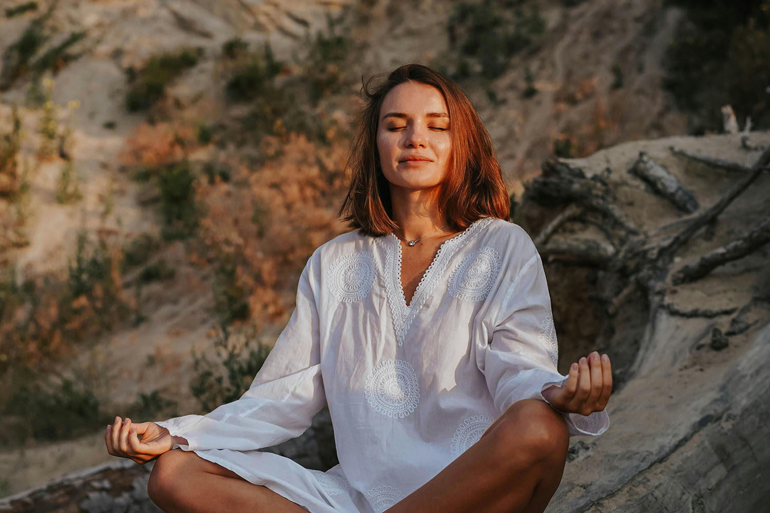 woman sitting in lotus pose while meditating outdoors