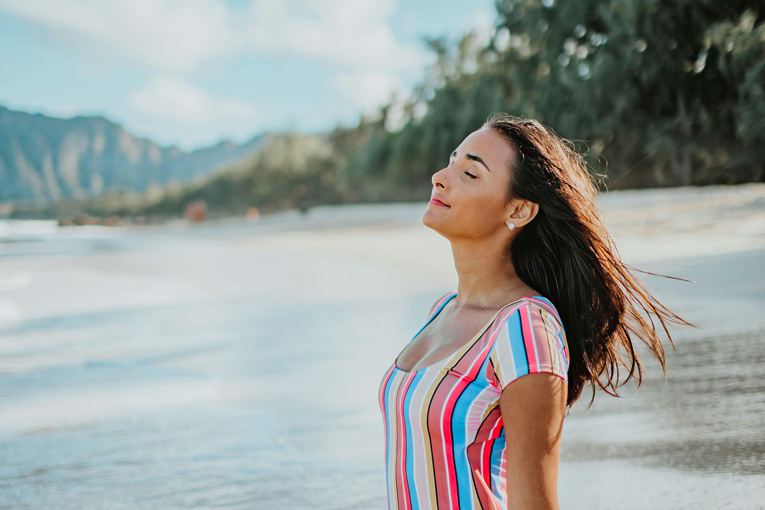 woman sitting on a beach and enjoying the breeze