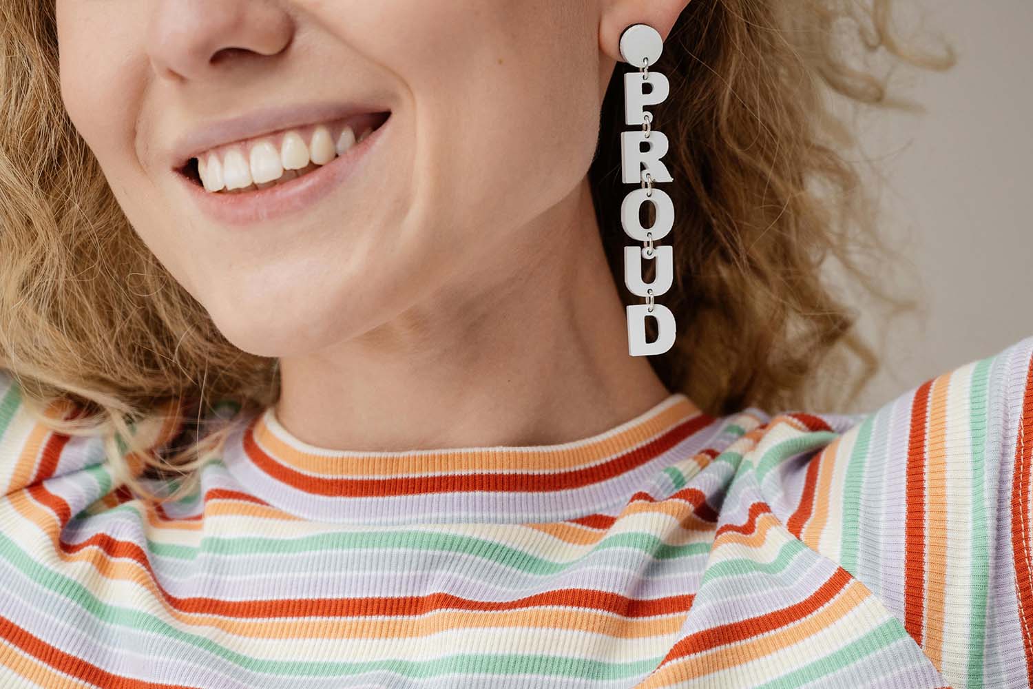 Smiling woman wearing an earring that spells the word 'proud'