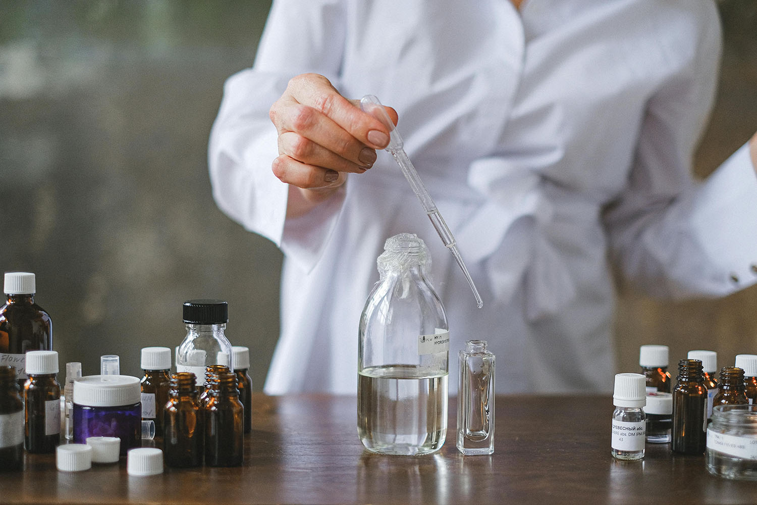 A scientist using dropper to transfer clear liquid to a glass bottle