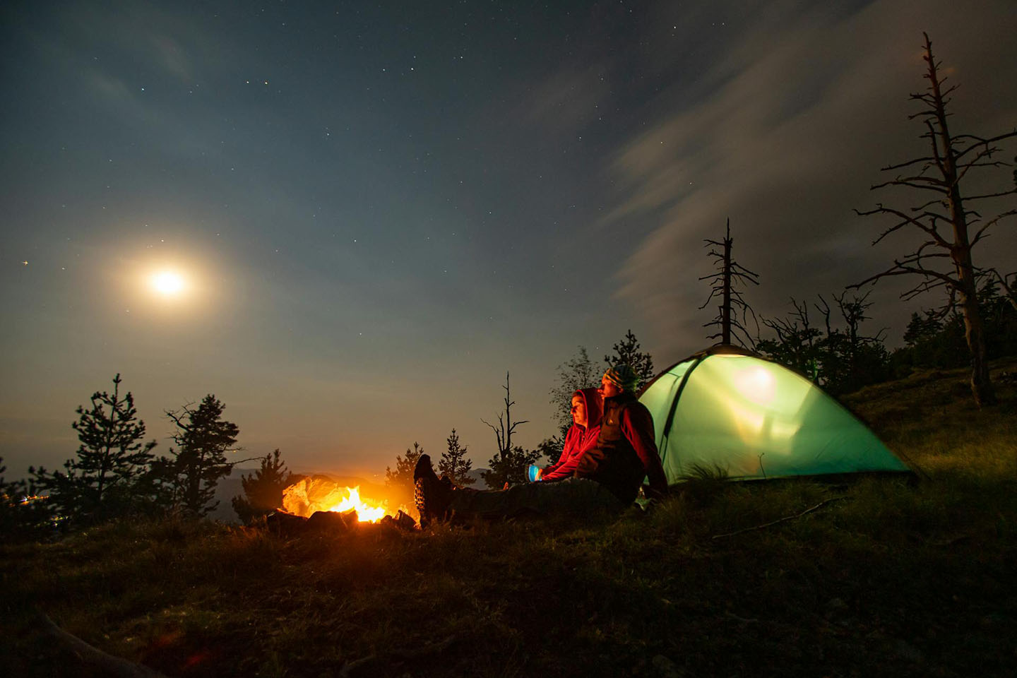 Two people sitting near a campfire