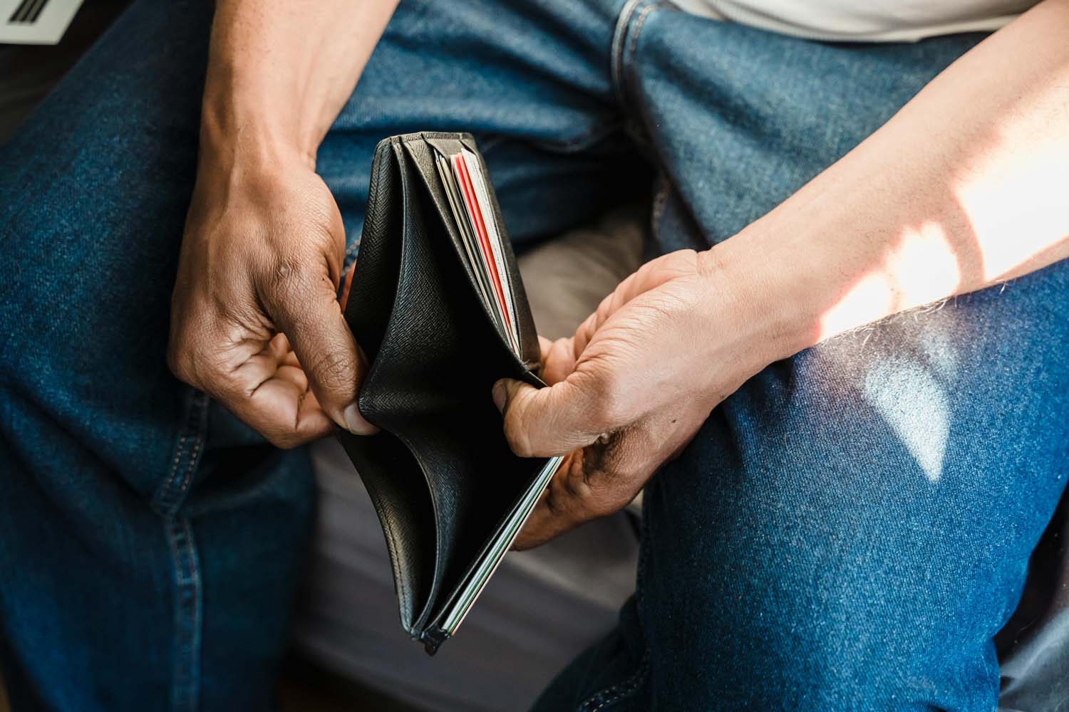 Person sitting on a couch holding open an empty wallet