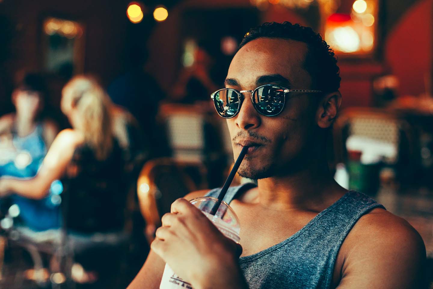 a man sipping on a cooler while sitting on a cafe