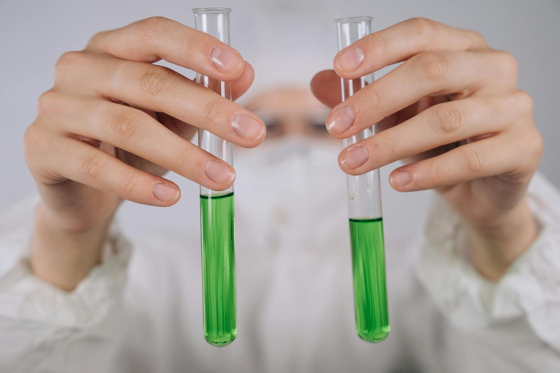 Person holding two glass vials of green liquid