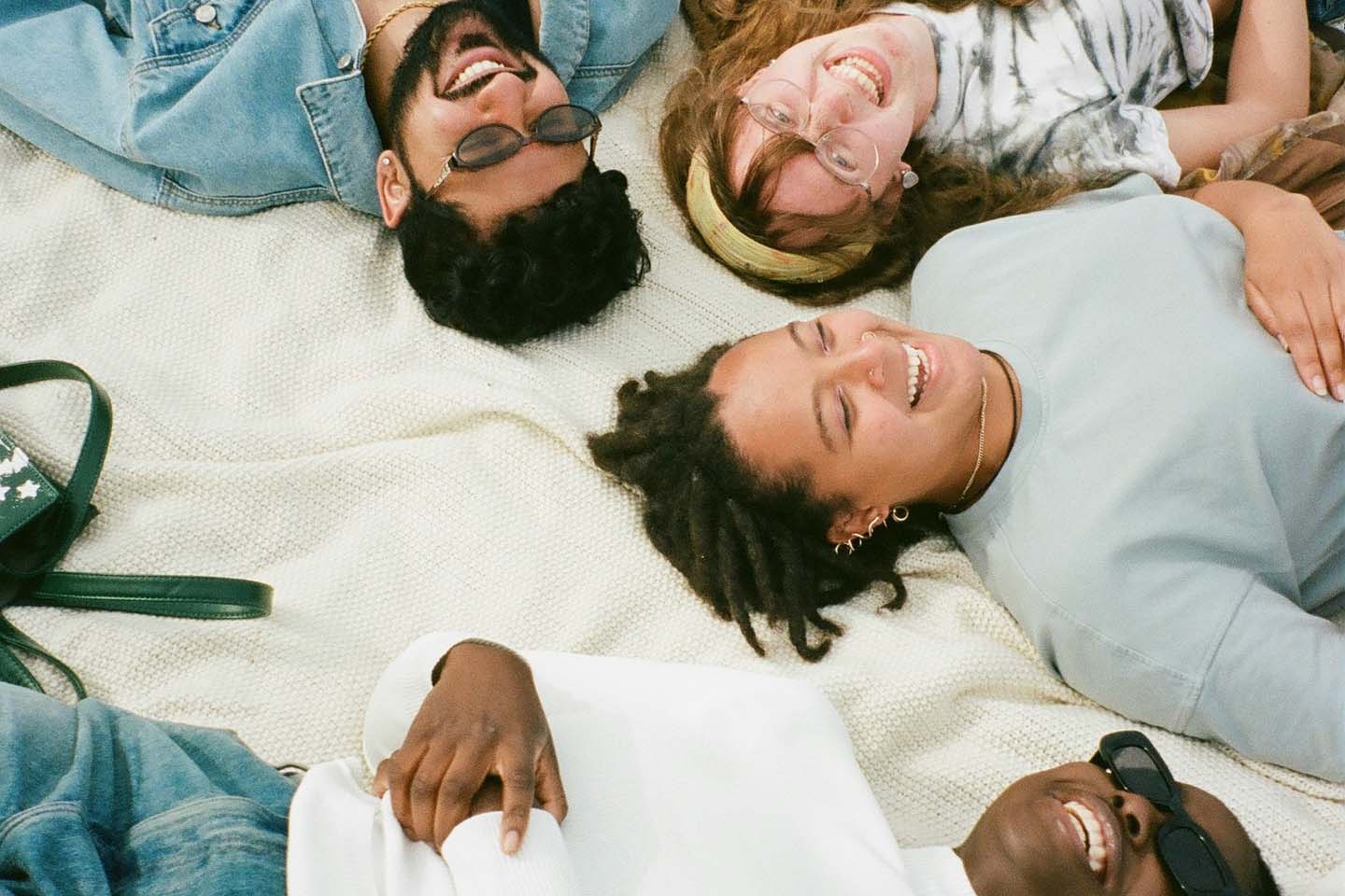 Group of friends smiling and relaxing on a picnic blanket