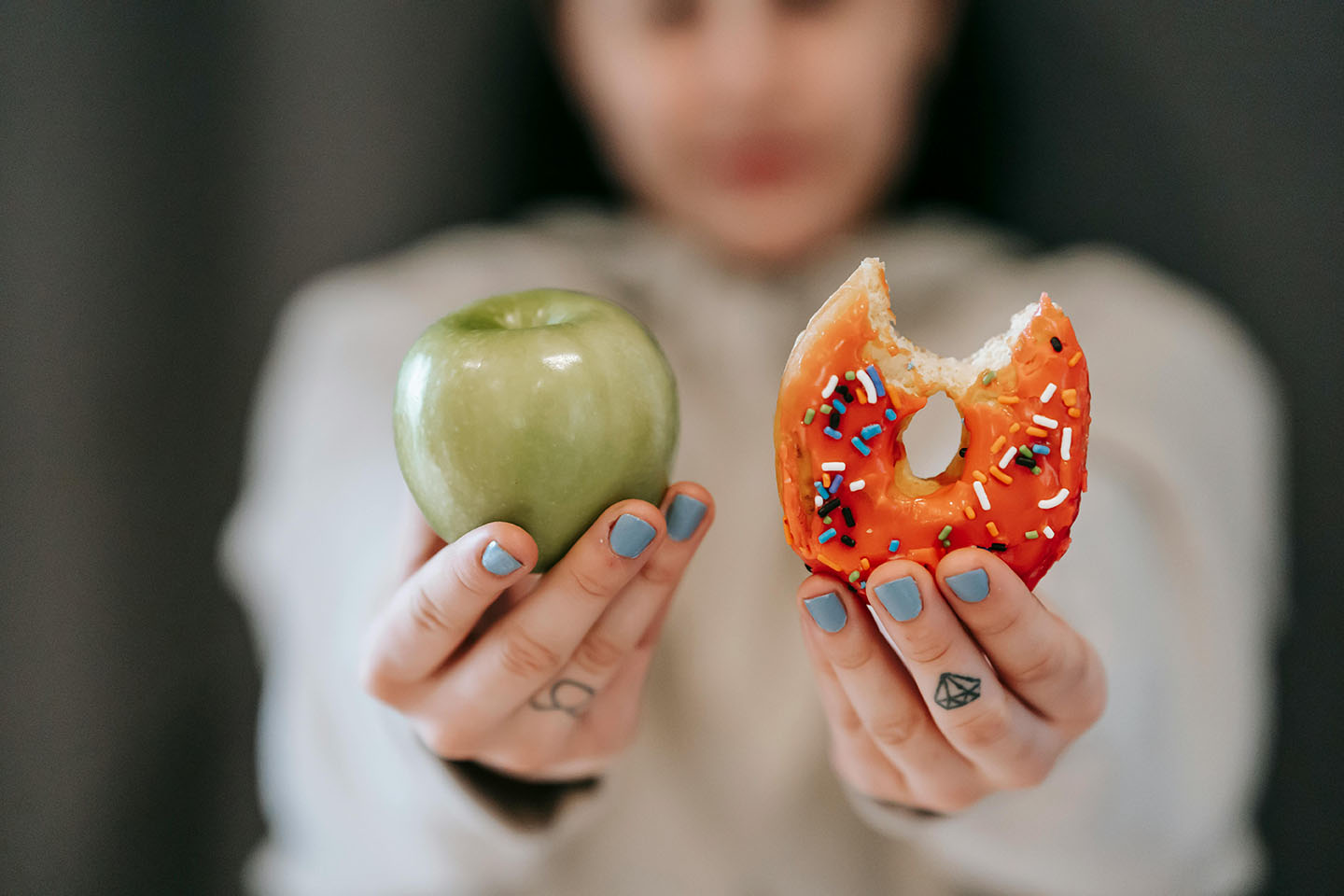 Person deciding between a donut and an apple