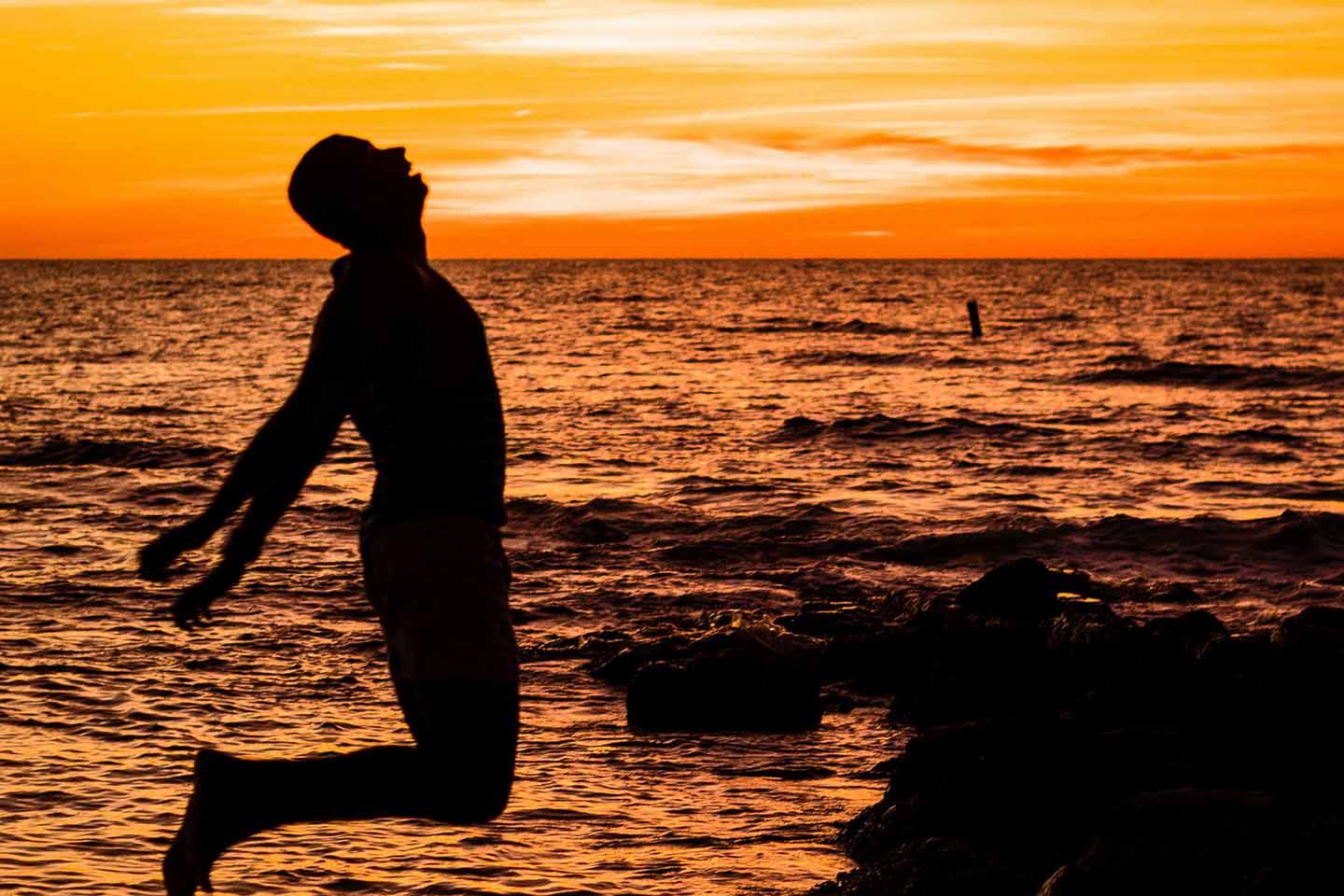Man jumping into the water at sunset